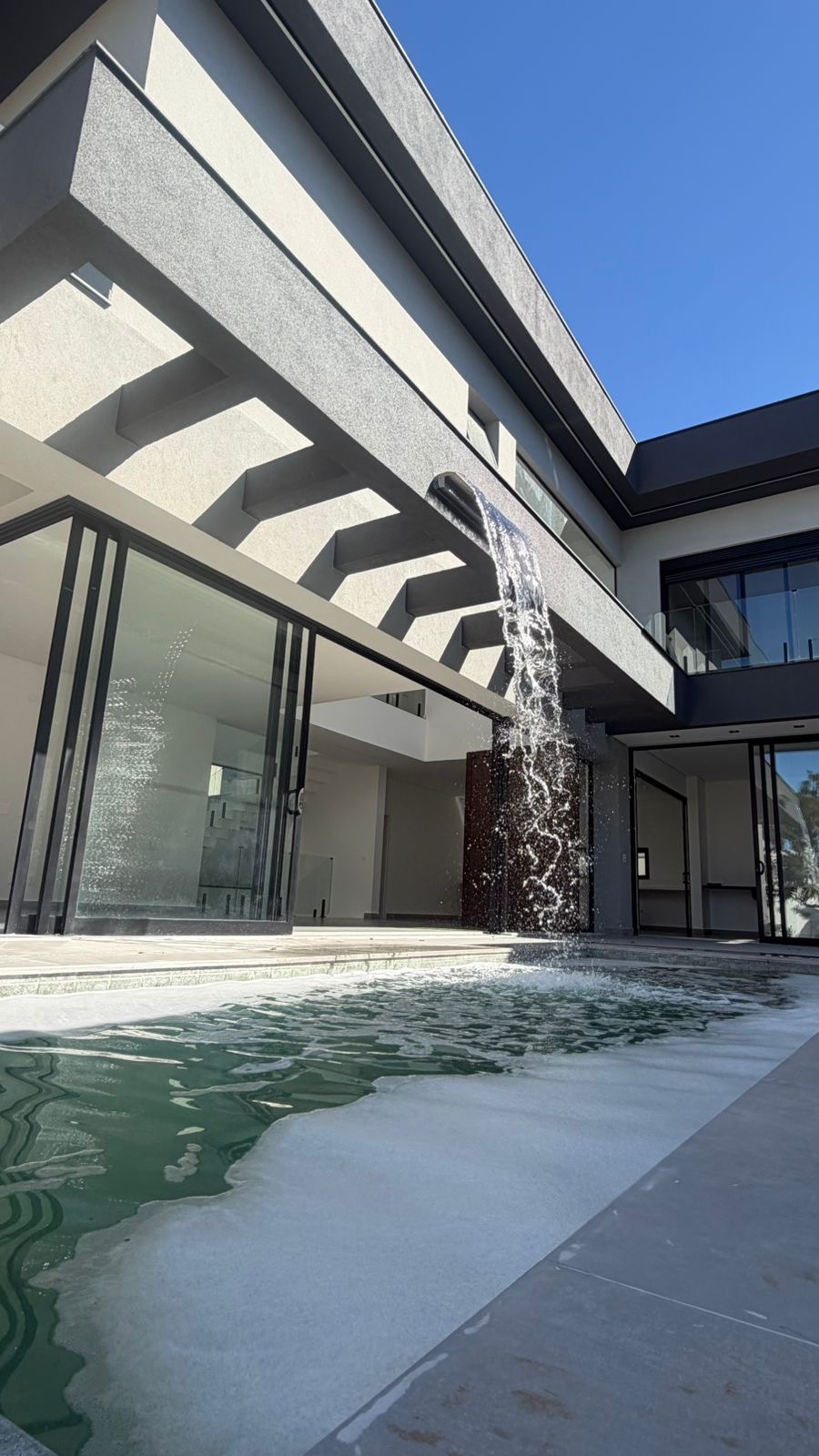 Piscina com cascata integrada à arquitetura