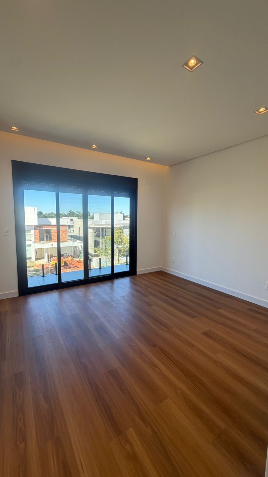 Suíte com varanda e esquadria de piso ao teto